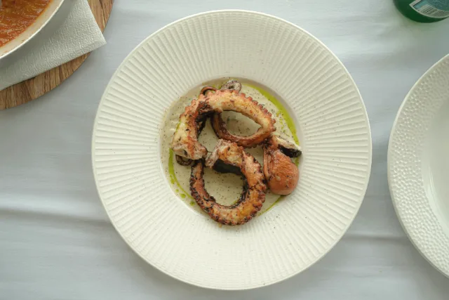 Pop a la brasa servit en un plat blanc amb oli d'oliva.